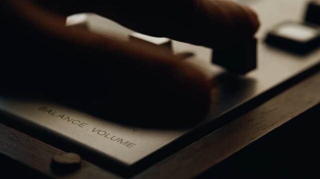 Closeup hand balancing volume on vintage digital audio mixer. Unknown man fader 