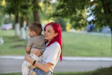 Fototapeta premium Beautiful young mother plays with her son in a summer park.