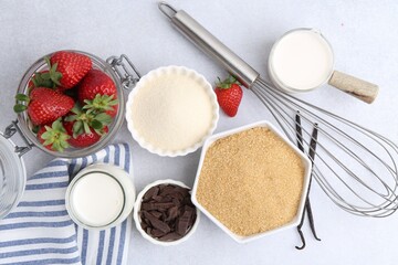 Different ingredients for panna cotta. Milk, sugar, vanilla, chocolate and strawberries on white table, flat lay