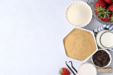 Different ingredients for panna cotta. Milk, sugar, vanilla, chocolate and strawberries on white table, flat lay. Space for text
