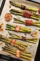 Tasty cooked asparagus with bacon and spices in baking tray, top view