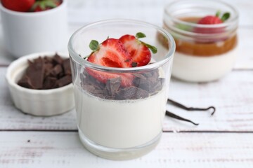 Tasty panna cotta with chocolate, strawberries and vanilla on white wooden table, closeup