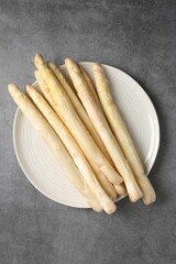 Raw white asparagus spears on grey textured table, top view