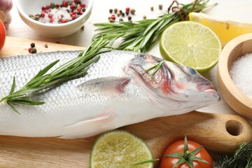 Fresh raw seabass with spices on white wooden table, closeup. Fish and seafood delicacies