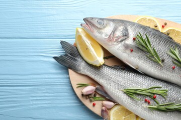 Fresh raw seabass fish with spices on blue wooden table, top view and space for text. Seafood delicacies