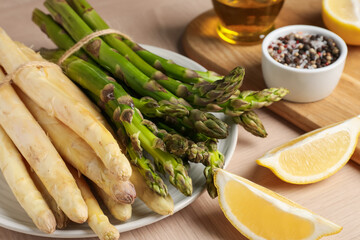 Different raw asparagus spears and spices on wooden table, closeup