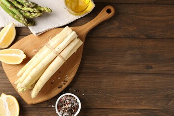 Green and white asparagus with spices on wooden table, flat lay. Space for text