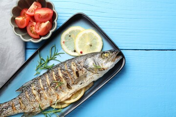 Homemade seafood dish. Tasty roasted seabass fish with spices and tomatoes on light blue wooden table, flat lay. Space for text
