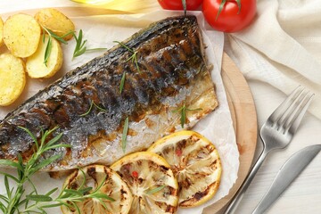Tasty roasted mackerel served with spices and vegetables on light wooden table, flat lay. Homemade seafood dish