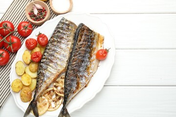 Homemade seafood dish. Tasty roasted mackerels with spices, tomatoes and potatoes on white wooden table, flat lay. Space for text