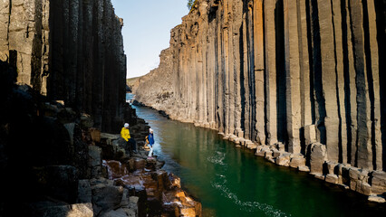 Explore the stunning beauty of Studlagil Canyon in Iceland, featuring towering basalt columns and a...