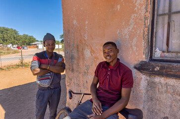 Africa village, african men resting on bicycle in front of the house, road nearby