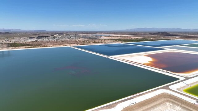 Aerial view of multi-colored evaporation ponds near the Palo Verde Nuclear Power Plant, creating a surreal landscape under a clear blue sky, Tonopah, Arizona, United States.