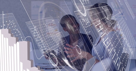 Women wearing navy and grey blazers analyzing transparent data panels in meeting room, with laptop