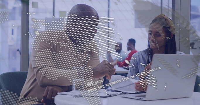 Man in sweater and woman in blouse reviewing printed documents in office, with digital map overlay