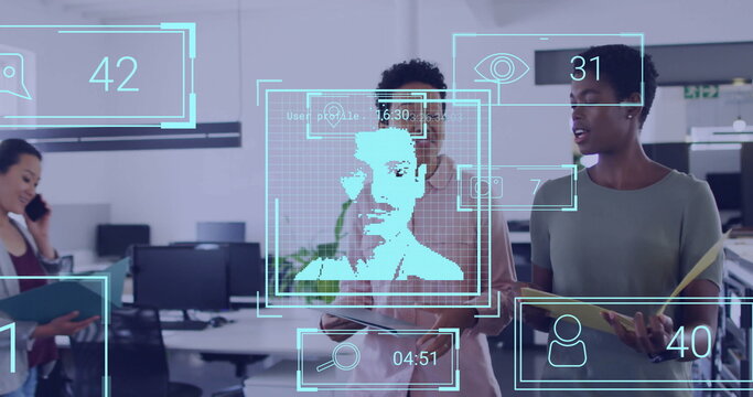 Collaborating women in blouses viewing facial recognition overlay in office, with smartphones - Powered by Adobe