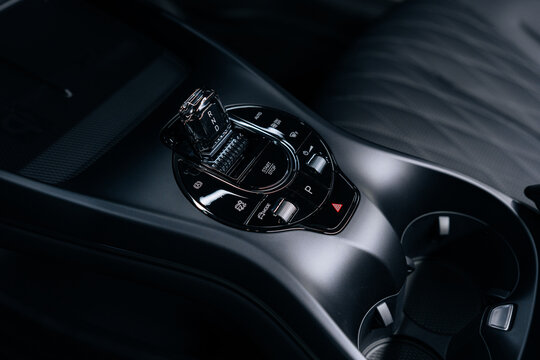 Close-up of BYD Seal center console – modern gear selector with driving modes, glossy black finish, dual cup holders and wireless charging pad for premium functionality in an electric sedan interior