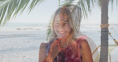 Overlaying smiling woman in red checkered top at beach with palm tree, hammock, ocean waves