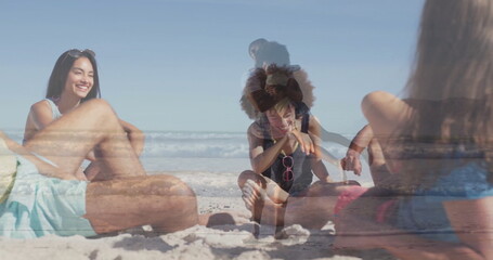 Fototapeta premium Relaxing group of adults and girl sitting on sandy shoreline, with pink sunglasses and beach towel