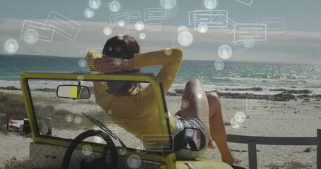 Leaning back woman wearing yellow top, striped shorts in dune buggy on shoreline, with chat icons