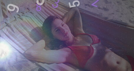 Reclining woman in red two-piece swimsuit relaxing on woven porch hammock, with floating numbers