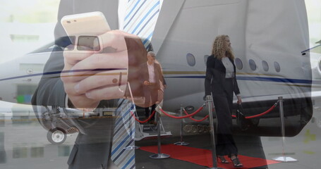 Checking smartphone man in dark suit in office, with passengers exiting private jet via red carpet
