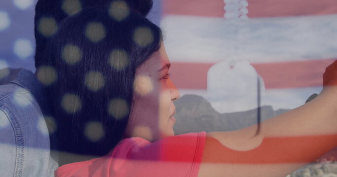 Standing couple wearing red t shirt, denim jacket overlooking mountains, with dog tags flag overlay - Powered by Adobe