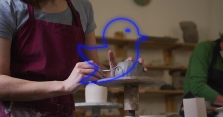 Man wearing red apron shaping vessel on pottery wheel in pottery studio, ribbon tool, copy space