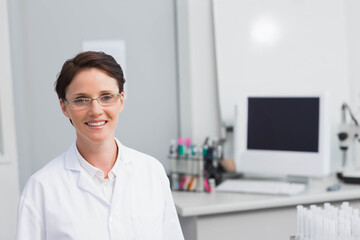 Female lab technician standing and smiling at medical lab with computer and microscope, copy space