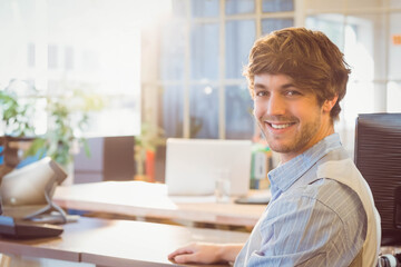 Male professional using telephone while holding glass of water at desk in modern office, copy space