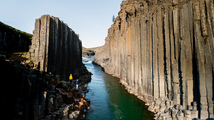 Exploring the breathtaking Studlagil Canyon in Iceland reveals magnificent basalt formations rising...