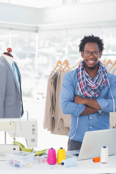 Worktable holding sewing machine, laptop and colorful thread spools under bright city window
