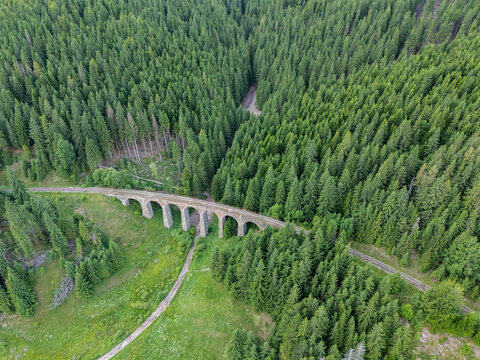 Aerial view of the Telg&Atilde;&iexcl;rt Viaduct, a stone arch bridge, nestled between a dense forest, showcasing a blend of engineering and natural beauty, Telg&Atilde;&iexcl;rt, Brezno District, Slovakia.