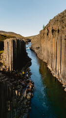 Studlagil Canyon in Iceland showcases stunning basalt columns rising majestically above a tranquil...