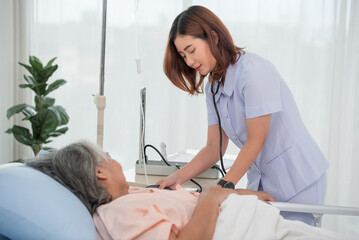 Asian nurse with tonometer measuring woman patient's blood pressure at hospital