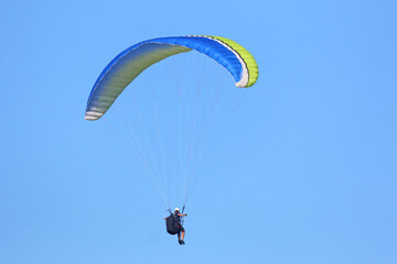Paraglider flying in a blue sky	