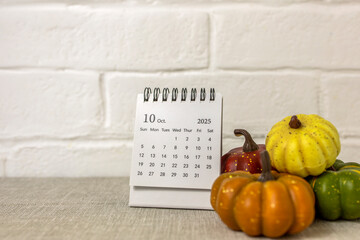 A desktop calendar for October 2025 and a pumpkin on the table. Halloween is coming soon.