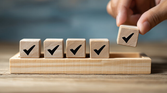 hand places a wooden block with a checkmark, completing a row of similar blocks. It symbolizes task completion, goal achievement, or project success. sense of accomplishment and progress