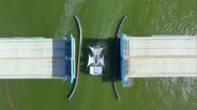 Aerial view of the 79th Street Causeway bridge amidst the dark green waters, a stark contrast to the white boat beneath, North Bay Village, Florida, United States.