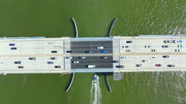 Aerial view of the 79th Street Causeway bridge, a concrete structure spanning over green waters with cars and a boat, North Bay Village, Florida, United States.