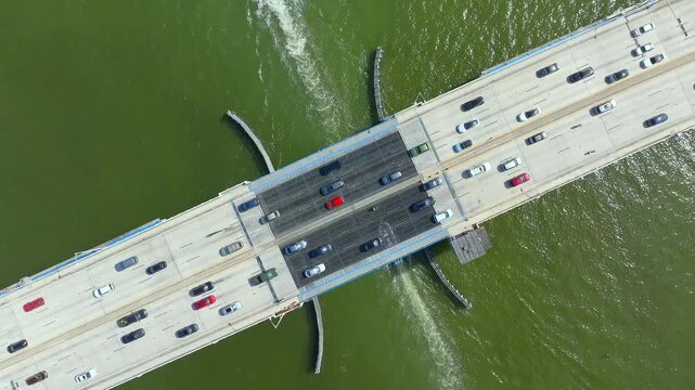 Aerial view of the 79th Street Causeway, a concrete bridge bustling with cars above the green water, creating a dynamic urban scene, North Bay Village, Florida, United States.