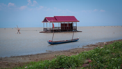 Floating Houseboat On Calm Water With Blue Boat And Red Roof