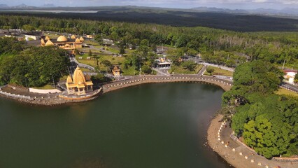 Drone photo of Ganga Talao temple complex nestled around a volcanic crater lake in Mauritius, a revered Hindu pilgrimage site surrounded by forest.