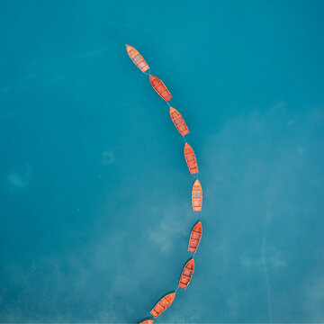 Aerial view of a sequence of rustic wooden boats on the shimmering turquoise waters of Lago di Braies, the jewel of the Dolomites, Prags, Trentino-South Tyrol, Italy.