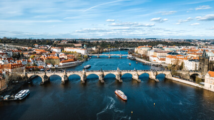 Aerial view of the iconic Charles Bridge gracefully arches over the Vltava River, connecting the old and new cities under a serene sky, Prague, Czechia.