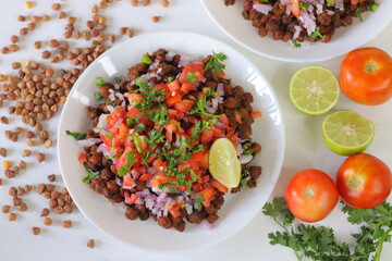 Chana Chat, also known as chickpea salad, served with chopped tomatoes, onions, cilantro, and lime