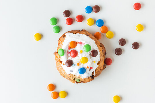 Fresh chocolate American chip cookie decorated with multicolored candies on white background. Flat lay of cookies with chocolate colored candies inside - Powered by Adobe
