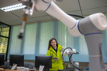Caucasian female robot arm programmer working on automated AI robotic arm upgrade software and...