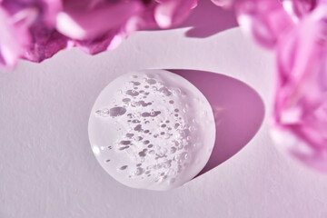 A drop of serum in close-up on a white background with lilac.