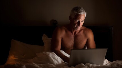 Mature man with laptop on the bed, no logos, no brands